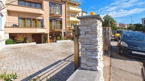 A multi-story residential building with a stone entrance, a paved driveway, and a parked car. - Apartment 1345/12663 (Istria - Pula), 2000m from the beach (Pula)