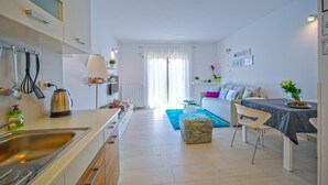 A modern kitchen with a sink, stove, and countertop. There is a dining area with a table and chairs. The room has a window with curtains and a plant on the windowsill. - Apartment 1345/12663 (Istria - Pula), 2000m from the beach (Pula)