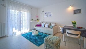 A modern living room with a sofa, a coffee table, and a dining area with a table and chairs. - Apartment 1345/12663 (Istria - Pula), 2000m from the beach (Pula)
