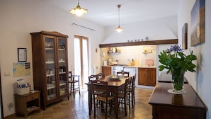 A kitchen with a dining table, chairs, and a cabinet. There are two pendant lights hanging from the ceiling. - Villa Raffaella (Massa Lubrense)