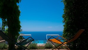 Two lounge chairs facing a pool with a clear view of the sea. - Villa Raffaella (Massa Lubrense)