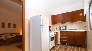 A compact kitchen with a refrigerator, oven, and wooden cabinets.