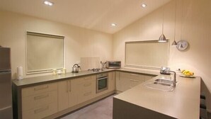 A modern kitchen with a central island, built-in oven, and a large window. - Carrot Cake Chalet - Ohakune (Ohakune)