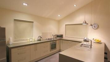A modern kitchen with a central island, built-in oven, and a large window.