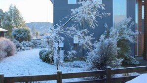 A modern two-story house with a covered driveway and snow-covered vegetation. - Carrot Cake Chalet - Ohakune (Ohakune)