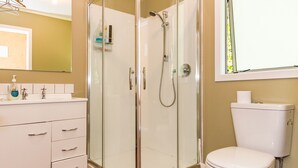 Une salle de bain moderne avec une douche à parois de verre, des toilettes blanches et un meuble-lavabo avec des tiroirs.