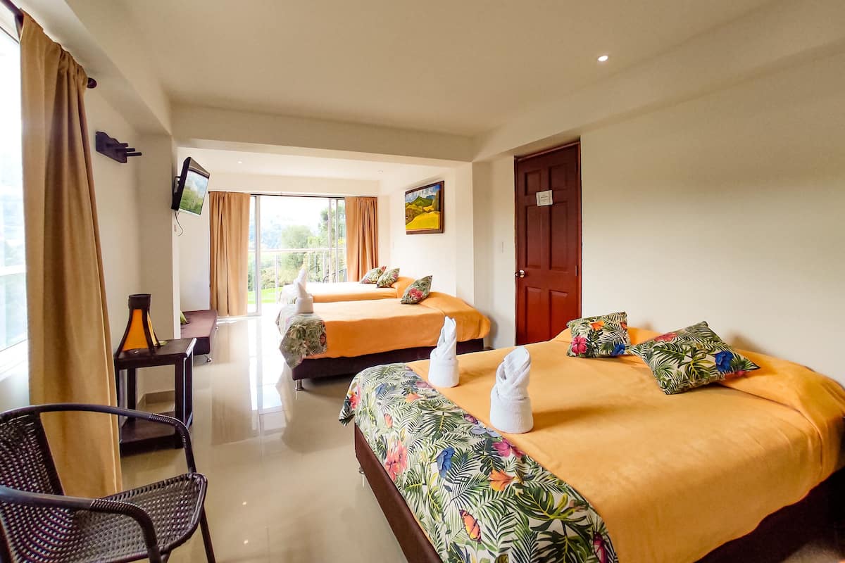 Habitación de hotel con dos camas, un televisor en la pared, un escritorio y una silla.