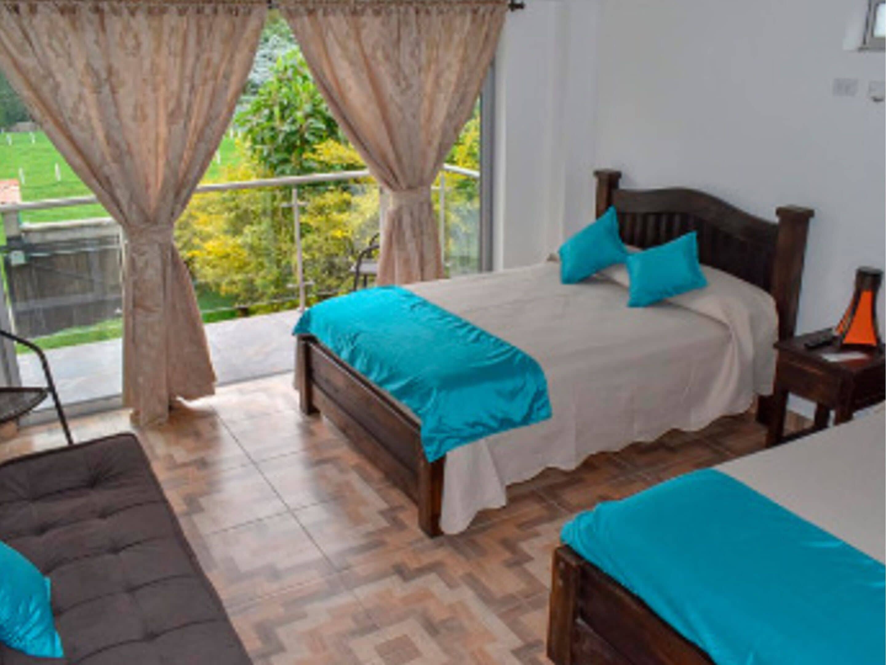 Une chambre à coucher avec un lit, une table de chevet, une lampe et une vue sur la verdure.