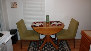 A dining table with two chairs, a green vase, and a patterned table runner. - Cozy Efficiency near University and town (BROWNWOOD)