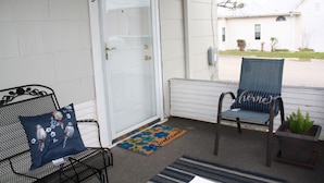 A porch with a white door marked with the number 3, a blue chair with a cushion, a metal bench, and a welcome mat. - Cozy Efficiency near University and town (BROWNWOOD)