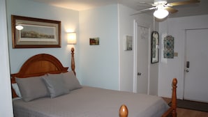 A bedroom with a wooden bed, a ceiling fan, and framed artwork on the walls. - Cozy Efficiency near University and town (BROWNWOOD)