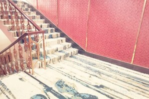 Una escalera con piso estampado y pared roja.
