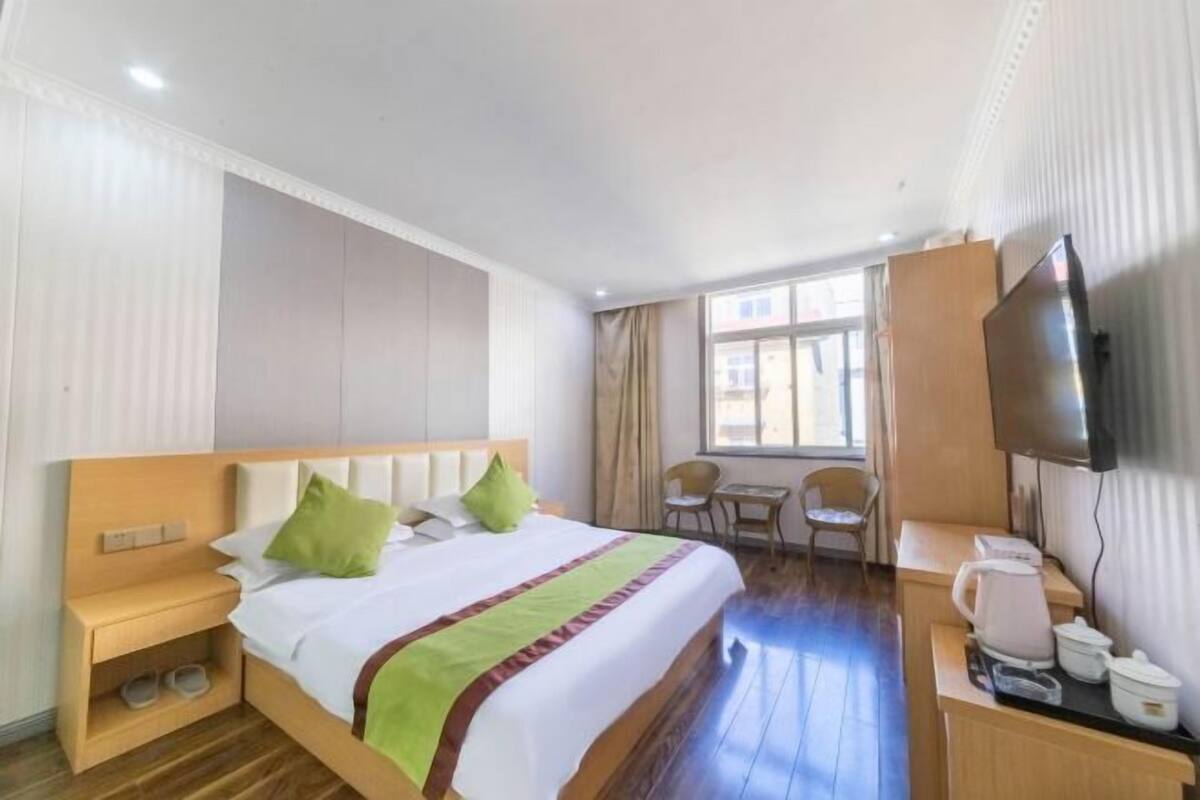 Ein Hotelzimmer mit Bett, Schreibtisch, Stuhl, Fernseher und Kaffeemaschine.