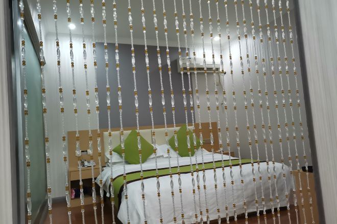 A bedroom with a bed, green pillows, and a white bedspread.