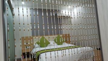 A bedroom with a bed, green pillows, and a white bedspread.
