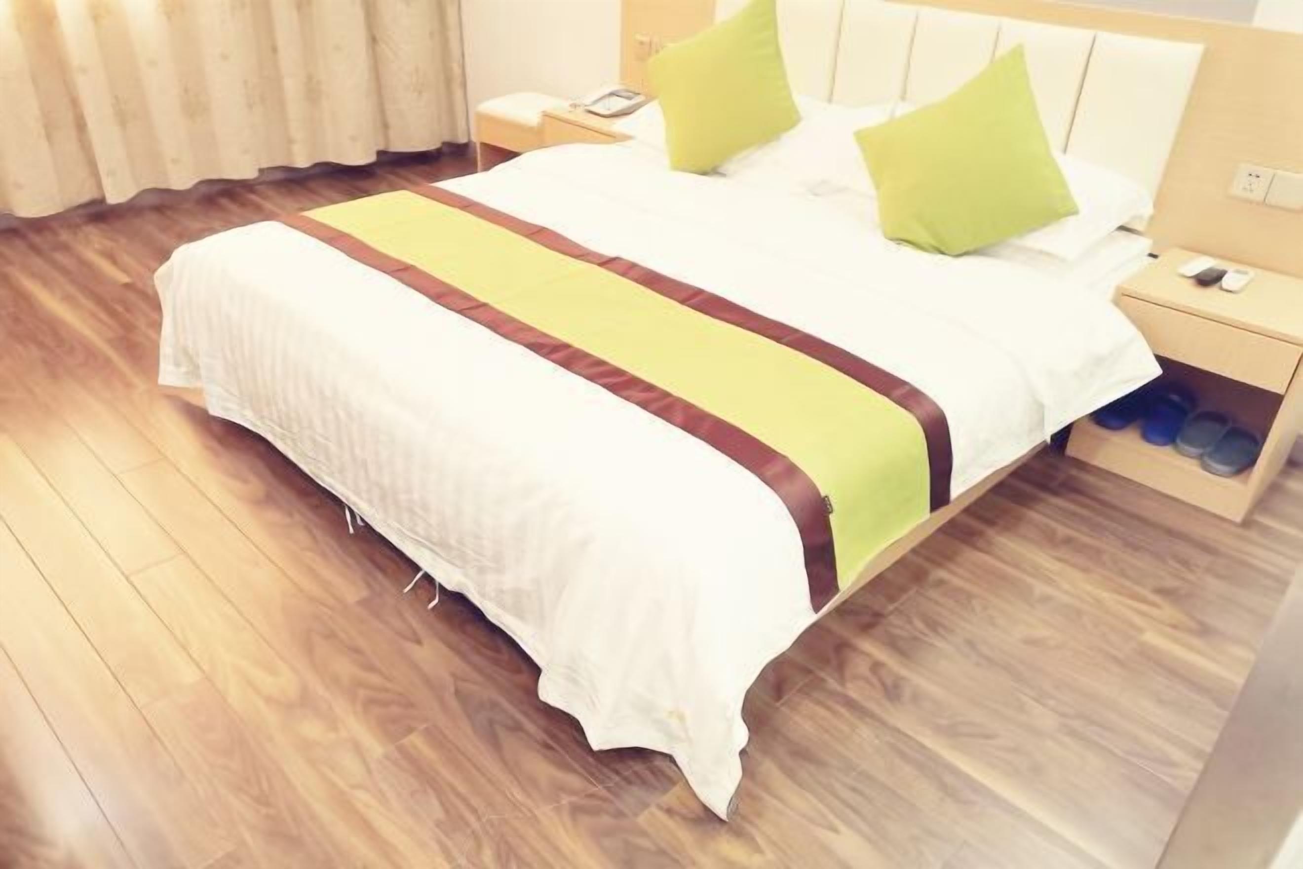Una habitación de hotel con cama, mesita de noche, teléfono y zapatero.