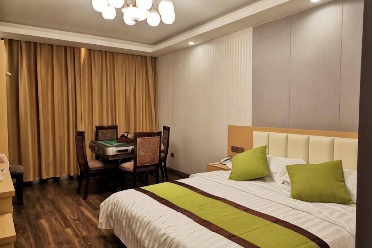 Ein Hotelzimmer mit Bett, Schreibtisch, Stuhl und einem Fenster mit Vorhängen.