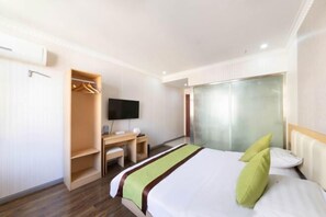 Una camera d'albergo con un letto, una scrivania, una TV e un armadio.