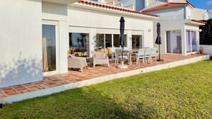 Une maison moderne dotée d’un patio aménagé avec des meubles d’extérieur et des parasols.