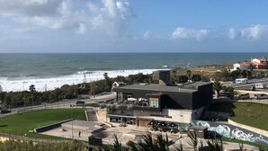 Une vue sur la côte, avec un bâtiment moderne doté d’une façade en verre, d’un espace extérieur aménagé pour se détendre et d’un skatepark.