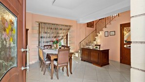 Un espace repas avec une table et des chaises en bois, un comptoir de cuisine et un escalier menant à un autre étage.