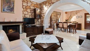 Un salon doté d’une cheminée en pierre, d’un téléviseur et d’un coin repas avec un escalier.