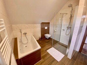 Un baño moderno con bañera, inodoro y ducha con mampara de vidrio.