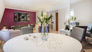 Ein modernes Wohnzimmer mit einem runden weißen Tisch, einem grauen Sofa und einer roten Akzentwand.