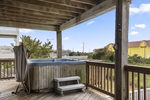 Eine Holzterrasse mit Whirlpool, einer Sitzbank und einem überdachten Bereich.