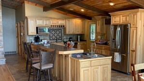 Una cocina amplia con armarios de madera, una isla grande con taburetes de bar y electrodomésticos de acero inoxidable.