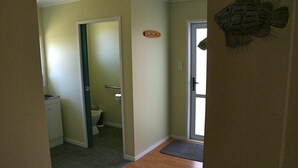 Un couloir avec des toilettes, un lavabo et une porte décorée avec un motif de poisson.