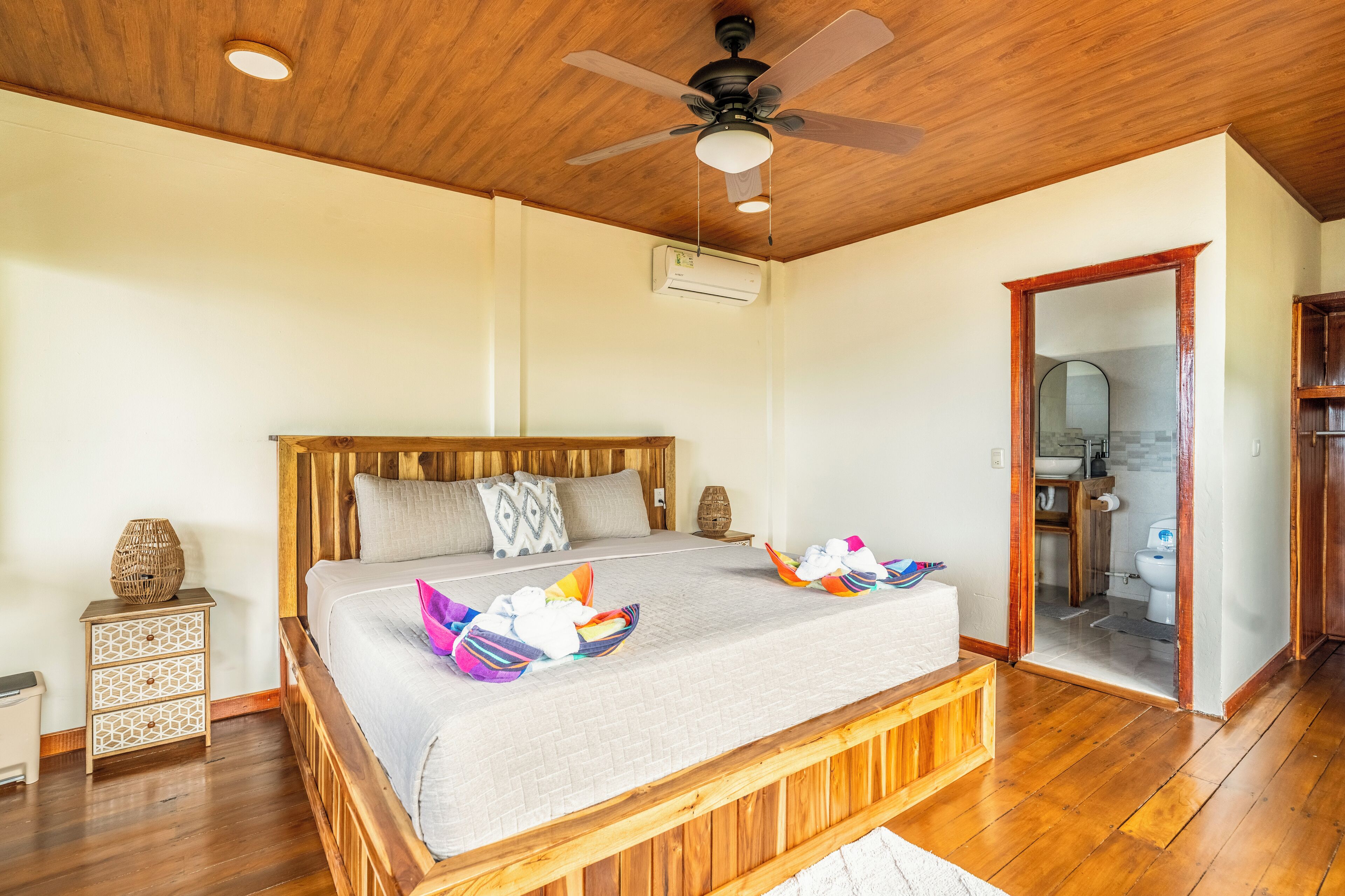 A spacious bedroom with a wooden bed, a ceiling fan, and a wooden floor.