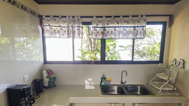 Una cocina con ventana, un lavamanos, una cafetera y un juguete.