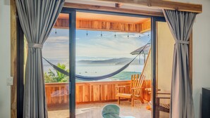 A room with a bed, a hammock, and a view of a beach and mountains. - Cotingas Ocean View (Drake Bay)
