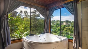A modern bathroom with a large bathtub, large windows, and curtains. - Cotingas Ocean View (Drake Bay)