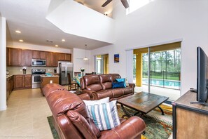 Relax in the living area with a view of the backyard, featuring a leather sofa set and coffee table.