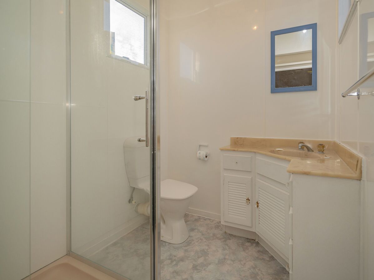 Un baño con cabina de ducha de vidrio, un inodoro y un lavabo con espejo.