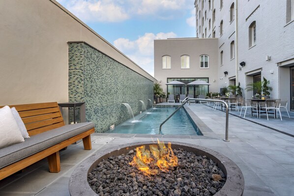 A pool area with a fire pit, seating, and outdoor tables.
