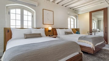 Habitación de hotel con dos camas, un ventanal grande, una obra de arte enmarcada y techo de madera.