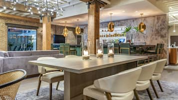 A modern bar area with a long counter, bar stools, and a large screen.