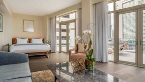 A hotel room with a bed, a sofa, a coffee table, and a large window with a view of the city. - ONE11 Hotel (New Orleans)