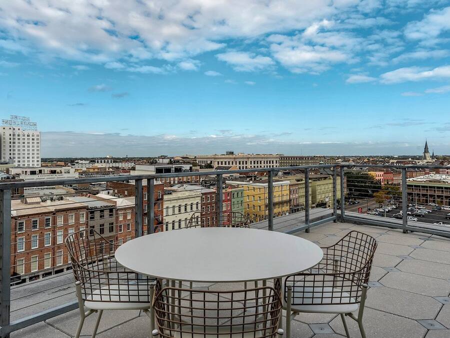Eine Dachterrasse mit einem runden Tisch und vier Stühlen, die einen weiten Panoramablick auf eine Stadtlandschaft mit historischen Gebäuden und einem Kirchturm bietet.