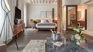 A modern hotel room with a bed, bedside table, and a view of the hallway. - ONE11 Hotel (New Orleans)