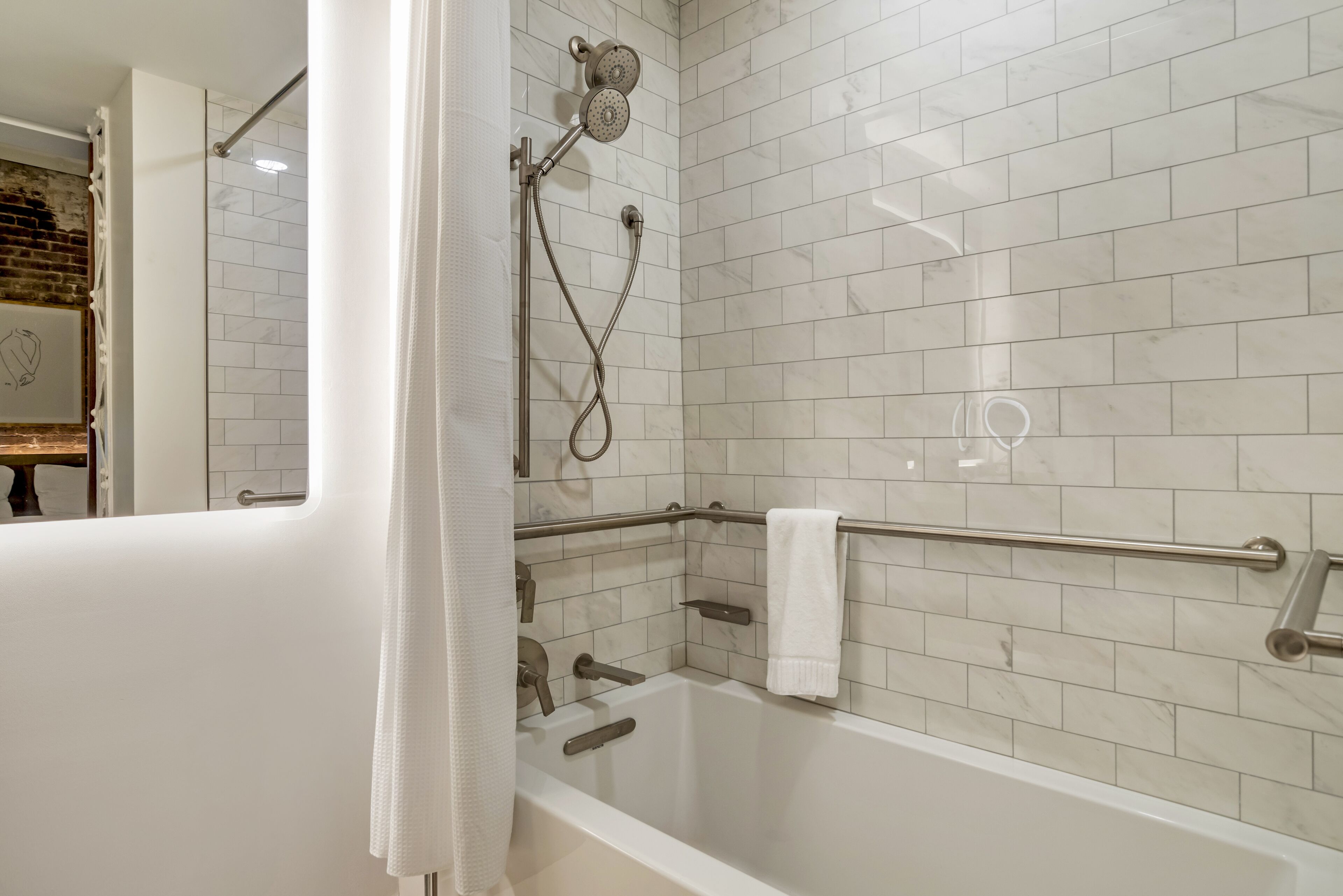 A modern bathroom with a bathtub, shower, and tiled walls.
