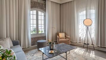 A modern living room with a sofa, a coffee table with a bottle of champagne, and a chair.