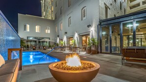 A courtyard with a pool, outdoor seating, and a large fire feature. - ONE11 Hotel (New Orleans)