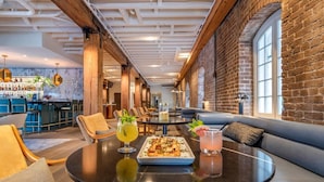 A modern lounge area with a bar, seating, and a pizza dish on a table.
