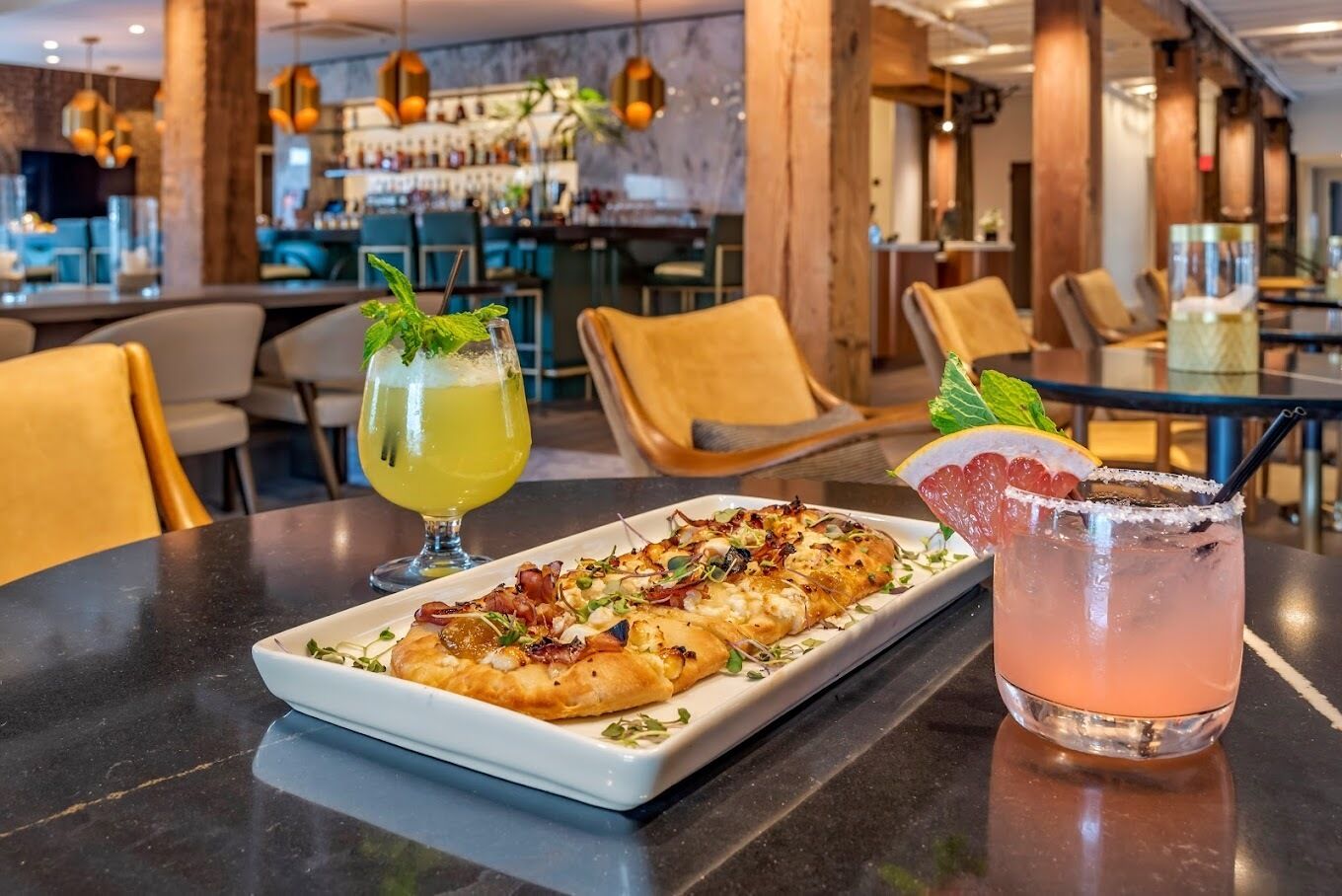Ein Restaurantambiente mit gedecktem Tisch für zwei Personen, darunter ein Gericht und zwei Getränke.