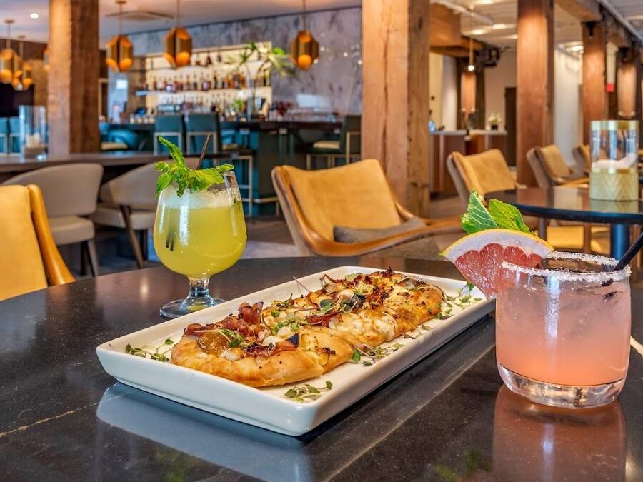 Ein Restaurantambiente mit gedecktem Tisch für zwei Personen, darunter ein Gericht und zwei Getränke.