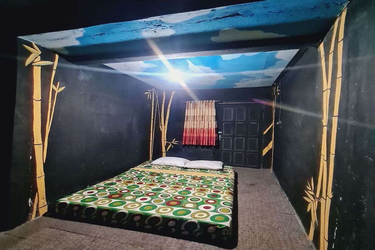 Una habitación con cama, puerta y paredes decoradas con motivos de bambú.